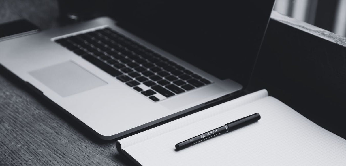 the hardest thing about writing - black and white image of laptop, notebook and pen on desk